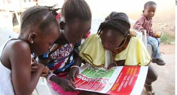 Meninas examinam cartaz do Unicef com informações sobre o ebola